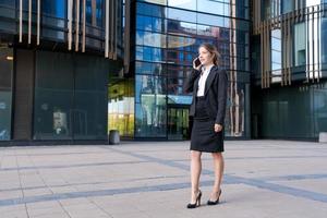 souriant affaires femme dans costume permanent sur ville rue contre toile de fond photo