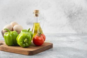 œufs de poule crus avec une bouteille en verre d'huile et de légumes frais photo