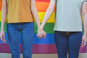 content lesbienne, magnifique asiatique Jeune deux femmes, fille gay ou lgbt, lgbtq couple l'amour moment dépenses bien temps, supporter ensemble en portant mains dans de face de fierté arc en ciel drapeau symbole sur isolé Contexte photo