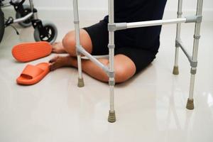 blessure d'une femme asiatique en tombant sur des surfaces glissantes avec une marchette à la maison. photo