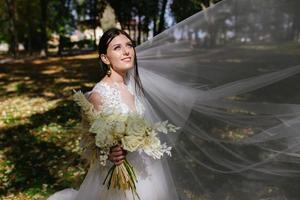 magnifique la mariée dans mode mariage robe sur Naturel arrière-plan.le étourdissant Jeune la mariée est incroyablement heureux. mariage journée. une magnifique la mariée portrait dans le forêt. photo