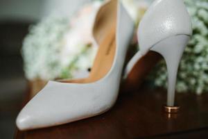 femelle pieds dans blanc mariage des sandales avec une bouquet de camomille photo