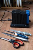 affûtage une couteau sur un électrique taille crayon à maison. flatlay couteau lame, ciseaux, aiguiseurs, poussière mouches sur le machine. photo