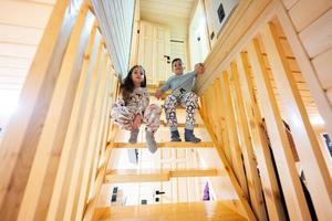 frère avec sœur dans pyjama asseoir sur escaliers dans confortable en bois minuscule cabine maison. la vie dans campagne. photo