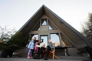 mère avec quatre les enfants asseoir sur terrasse de la grille minuscule maison dans le montagnes. photo