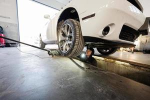 mécanicien dans une station de réparation de service travaillant avec muscle car. un ouvrier inspecte avec un briquet la partie courante de la roue. photo