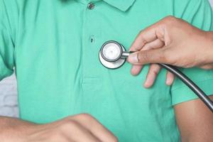 Médecin à l'aide d'un stéthoscope sur personne portant une chemise verte