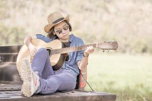 femme portant un chapeau et jouant de la guitare sur une camionnette photo