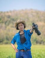 femme porter un chapeau et tenir des jumelles dans un champ d'herbe photo