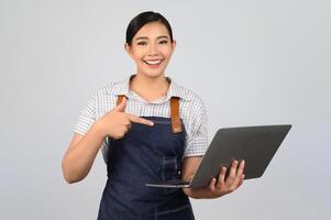 portrait de jeune femme asiatique en uniforme de serveuse pose avec un ordinateur portable photo