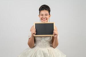 jeune belle mariée asiatique pose avec un tableau blanc à la main photo