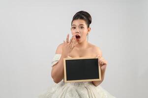 jeune belle mariée asiatique pose avec un tableau blanc à la main photo