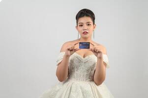 jeune belle mariée asiatique affichant avec carte de crédit en main photo