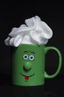marrant vert tasse avec une de bonne humeur visage avec fouetté crème. un revigorant boisson dans le Matin. photo