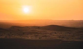 le coucher du soleil à le bord de le roulant le sable dunes dans le vide trimestre arabe désert à l'extérieur abu dhabi, uni arabe émirats photo