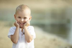 Beau peu garçon souriant et à la recherche à le caméra. une magnifique enfant pour une marcher. photo