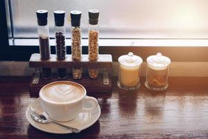 une tasse de chaud café latté sur en bois table fermé à le la fenêtre. photo