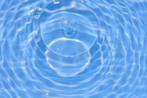 défocalisation floue transparente bleu clair texture de surface de l'eau calme avec des éclaboussures et des bulles. fond de nature abstraite à la mode. vagues d'eau au soleil avec espace de copie. éclat de l'eau bleue photo