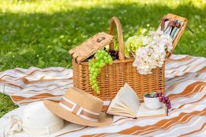 sur une vert pelouse, une mignonne paille pique-nique panier contre le toile de fond de une magnifique été la nature. des loisirs, Extérieur pique-nique, famille traditions, romance. photo