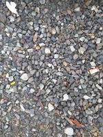 texture du sol de petites roches grises. fond de pierre noire petite route. texture transparente de pierre cailloux de gravier. fond sombre de gravier de granit concassé, gros plan. argile agglomérante photo