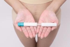 femme en gros plan utilisant une injection de traitement de fiv sur le ventre pour préparer la fertilité reproductive , la stimulation de l'ovulation . photo