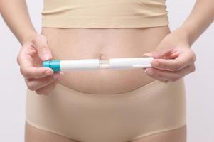 femme en gros plan utilisant une injection de traitement de fiv sur le ventre pour préparer la fertilité reproductive , la stimulation de l'ovulation . photo
