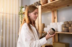 une Jeune femme entrepreneur en portant tablette vérification artisanat des produits à vente à les clients dans sa magasin photo