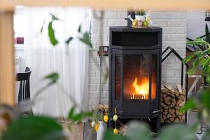 Pâques décor près cheminée le fourneau avec Feu et bois de chauffage. confortable Accueil foyer dans intérieur avec mis en pot des plans, coloré Pâques œufs, Pâques lapin et bouquet. printemps dans une pays maison photo