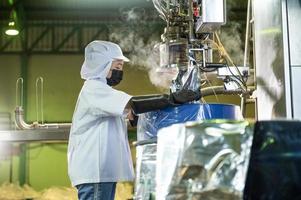 femelle ouvrier dans une ketchup usine maîtrisé automatique aseptique remplissage machine remplissage ketchup dans grand cuves à un industriel établissement dans Asie. nourriture industrie industrie agro-alimentaire. photo