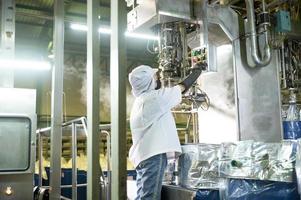 femelle ouvrier dans une ketchup usine maîtrisé automatique aseptique remplissage machine remplissage ketchup dans grand cuves à un industriel établissement dans Asie. nourriture industrie industrie agro-alimentaire. photo