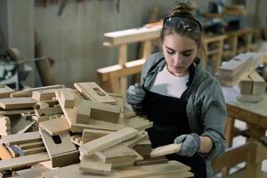 Jeune femelle Charpentier travail projet dans sa atelier. femelle Charpentier fabrication en bois meubles. photo