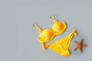 Jaune maillot de bain et étoile de mer sur une gris Contexte. photo