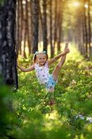 le peu fille soulève sa jambe en haut, gymnastique des exercices dans le forêt. photo