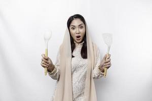 excité asiatique musulman femme portant une foulard, en portant cuisine vaisselle et souriant, isolé par blanc Contexte photo