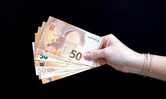 femme main en portant cinquante euro billets de banque sur une noir Contexte. photo