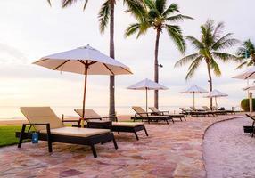 Parapluie et chaise autour de la piscine de l'hôtel resort avec lever de soleil le matin photo