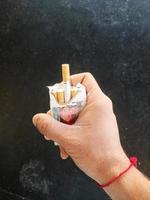 homme main en portant cigarette paquet. fumeur une cigarette photo