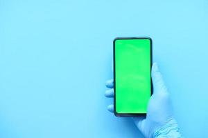 main du médecin tenant un téléphone intelligent avec écran vert
