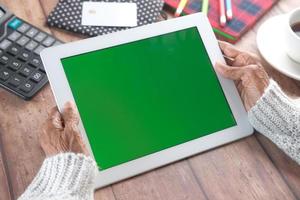 Femme plus âgée tenant une tablette numérique avec écran vert photo