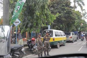 Tegal, décembre 2022. une groupe de gens marchait vers le bas une occupé ville rue, en utilisant divers modes de transport le long de le des arbres et les plantes. photo