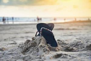 retourner flops sur plage avec sablonneux plage le coucher du soleil et océan mer Contexte photo