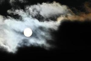 Soleil disque derrière rétro-éclairé des nuages photo
