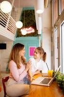 Jeune mère et sa fille travail sur portable et en buvant Frais Orange jus dans le café photo