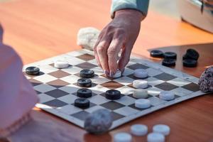 tournoi de dames en plein air sur papier damier sur table, gros plan des mains des joueurs photo