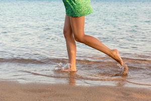 magnifique fille jambes fonctionnement sur le plage. jolie fille en marchant sur l'eau photo