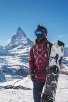 Jeune snowboarder dépenses hiver vacances dans zermatt, près le célèbre Matterhorn culminer. Masculin posant dans Suisse Alpes pour le planche a neige saison. photo