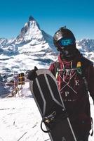 Jeune snowboarder dépenses hiver vacances dans zermatt, près le célèbre Matterhorn culminer. Masculin posant dans Suisse Alpes pour le planche a neige saison. photo
