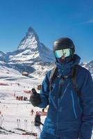 Jeune skieur profiter Zermatt ski station balnéaire. magnifique ensoleillé journée avec une skieur en haut dans le montagnes. des sports modèle. photo