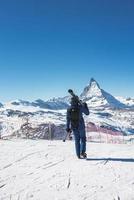 Jeune skieur profiter Zermatt ski station balnéaire. magnifique ensoleillé journée avec une skieur en haut dans le montagnes. des sports modèle. photo