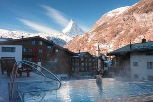 Jeune homme nager à l'intérieur le luxe infini en plein air bassin avec un incroyable vue à le Matterhorn de pointe dans zermatt, Suisse. photo